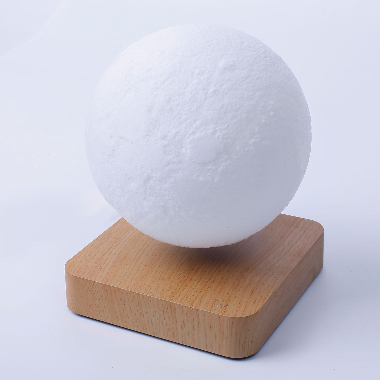 White spherical object on a wooden base against a light gray background